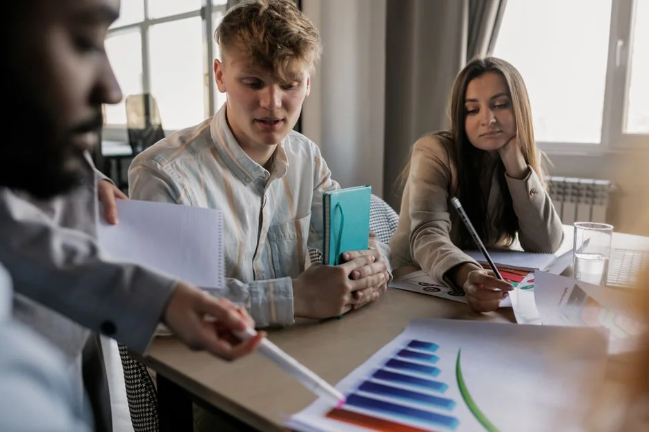 Un espace de travail contemporain où des mains examinent des données marketing sur un ordinateur portable et des documents papier.
